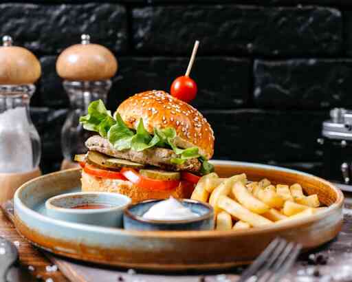 side-view-chicken-burger-with-pickles-tomatoes-served-with-french-fries-sauces-dark